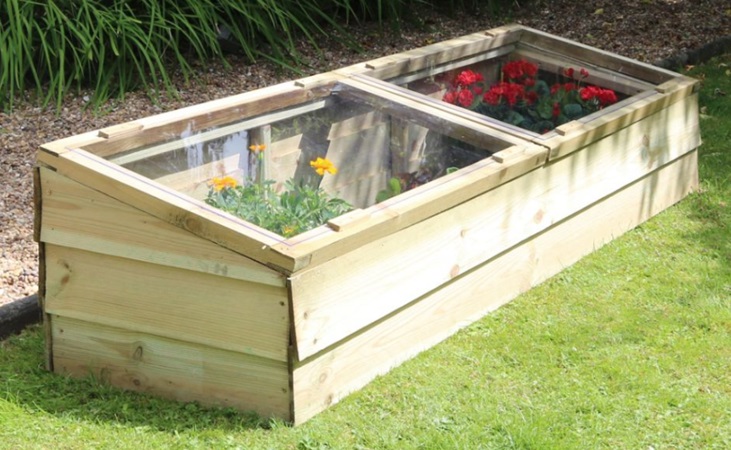 a wooden cold frame in the garden with flowers inside